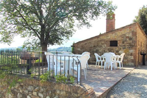 open-air living spaces with barbeque and tables  at farm house rental near Siena